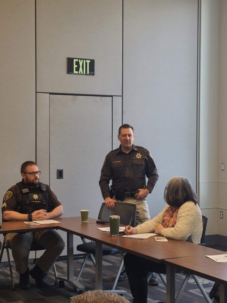 law enforcement officers presenting to people around a table
